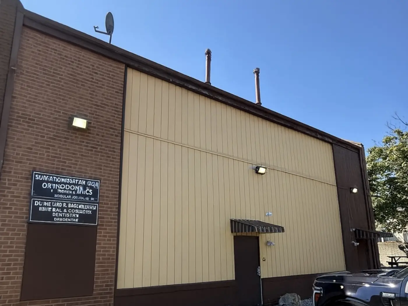 The same wall after painting: the panels in an even warm tan, with the base course, trim, and door in a deep brown that squares the wall off against the brick.